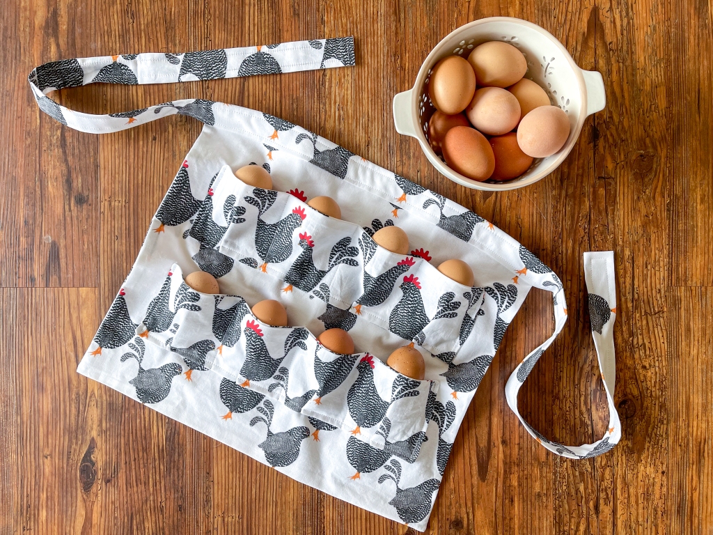 Finished egg collecting apron with farm fresh eggs in the pocket and in a white bowl