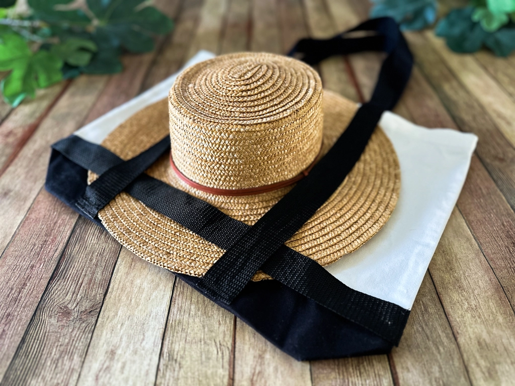 Side view of a stylish sun hat neatly tucked into a handmade tote bag, perfectly arranged for a chic summer outing.