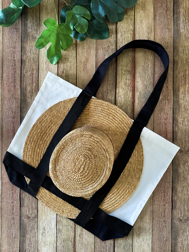 Overhead view of a stylish sun hat neatly tucked into a handmade tote bag, perfectly arranged for a chic summer outing.